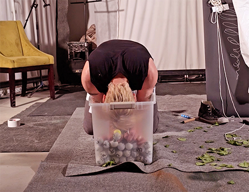 Performance artist Scotch Wichmann diving into a tub of 200 golf balls